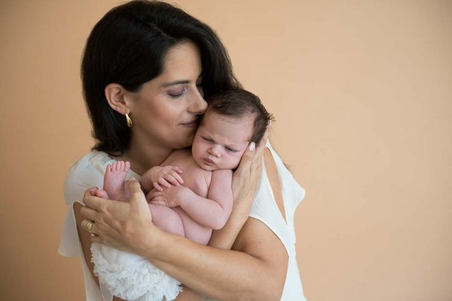 mãe beijando filha recém-nascida em ensaio newborn no estúdio fotográfico laura alzueta em São Paulo