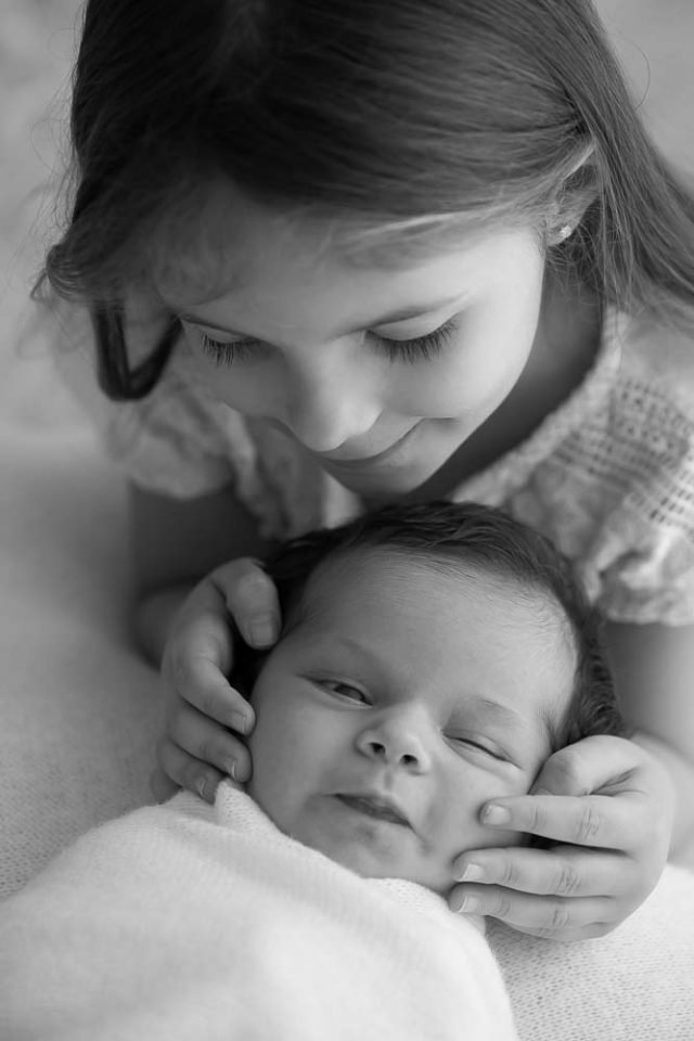 foto preta e branca mãe beijando filha recém-nascida em ensaio newborn no estúdio fotográfico laura alzueta em São Paulo