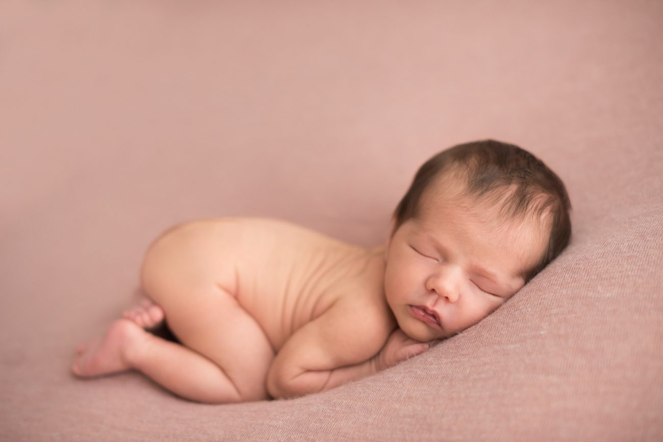 bebê recém-nascido pelado em puff com manta rosa em estúdio de fotografia newborn laura alzueta em pinheiros sp